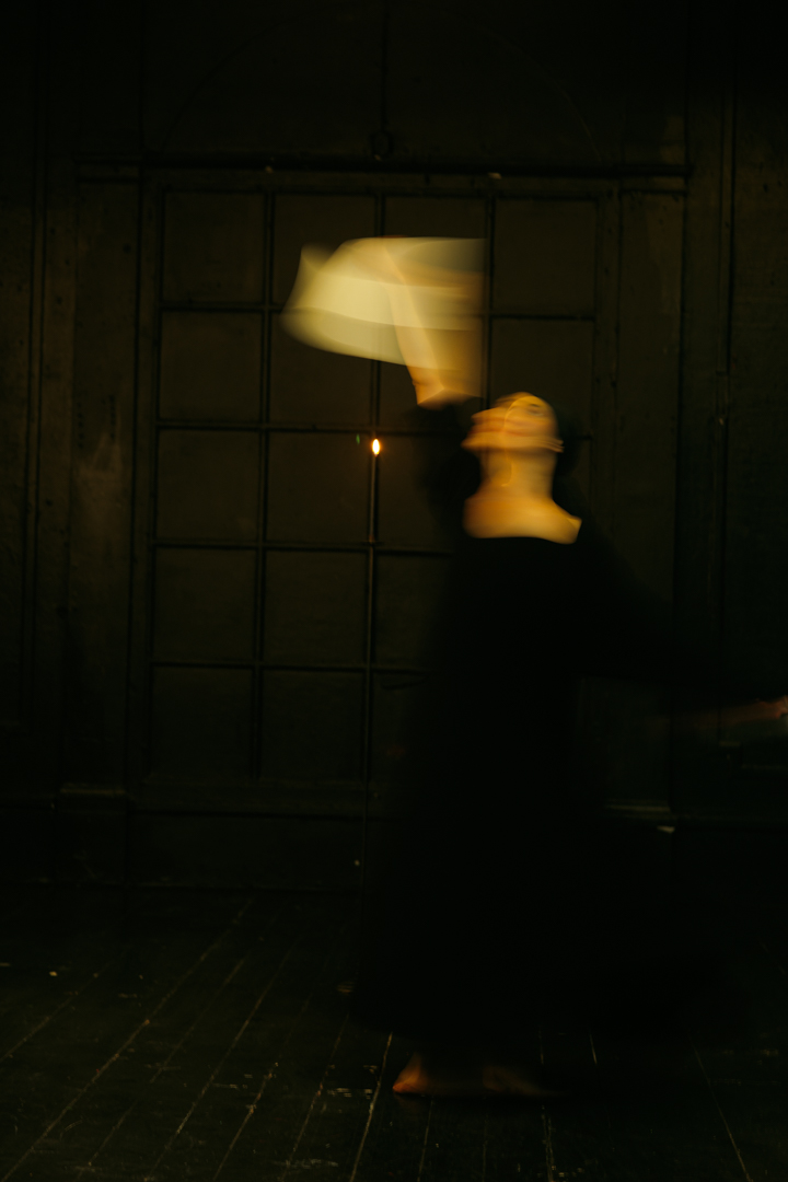 A dancer turning by candlelight, a pale cloth trailing through the air.